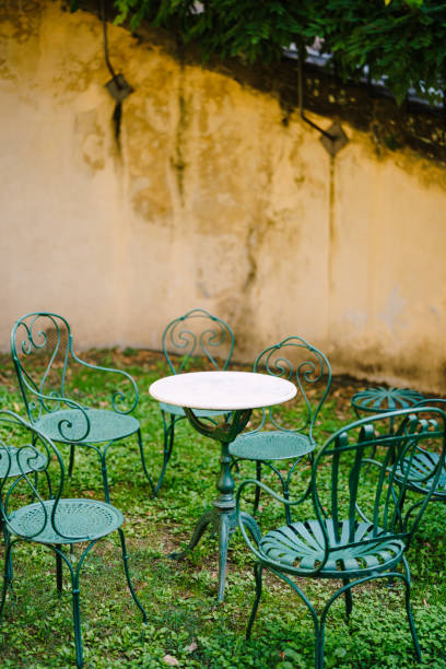 istock White small cocktail table surrounded by six green forged metal chairs. 1220369986