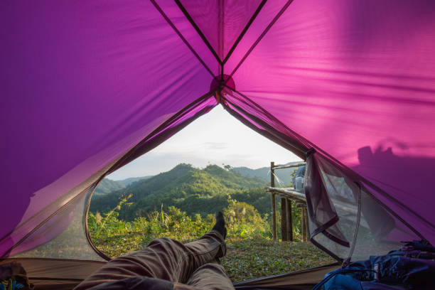 istock Man have on long pants lying down in the purple tent look mountain view 1220371274