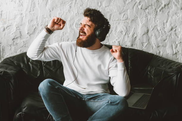 istock young joyful man listening music and relaxing on sofa 1220371743