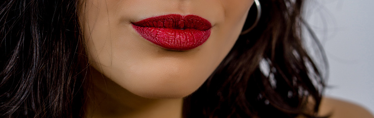 Close up macro photo view of beautiful girl lips with red matt lipstick. Part of face, young woman facial details.