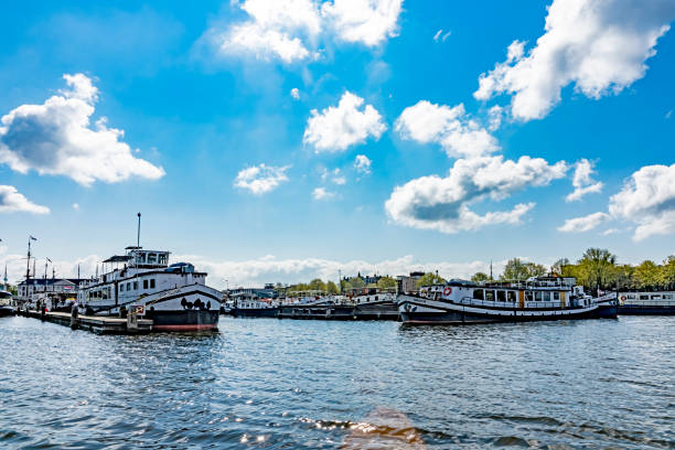 View across the Amstel river in Amsterdam, Netherlands. There are tour boats moored in the foreground.