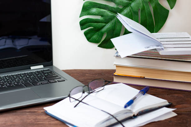 istock Notebook, books and notepad for notes on a dark wooden table. The concept of remote work and self-study at home in quarantine. 1220383633
