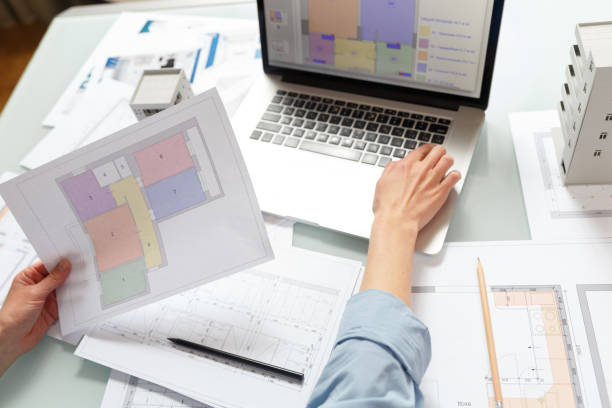 istock Interior designer working with an apartment plans in a studio, with blueprints and laptop on a table. 1220385230