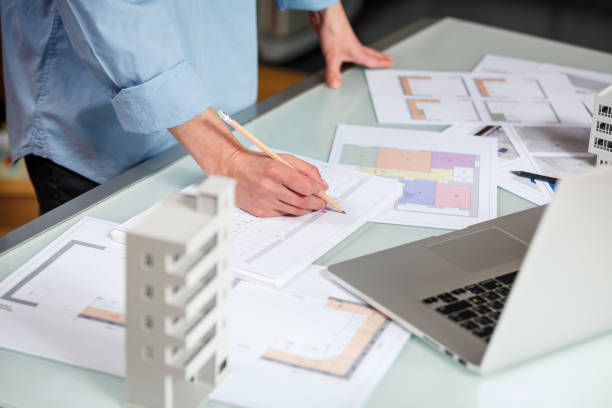 istock Interior designer working with an apartment plans in a studio, with blueprints and laptop on a table. 1220385257