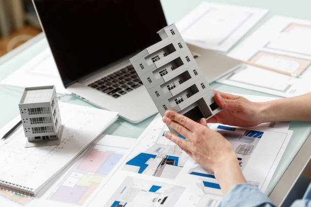 istock Close up of a house model in architect's  hands in a construction bureau. 1220385317