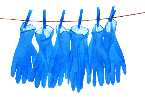 blue medical gloves hanging on a rope isolated on white background