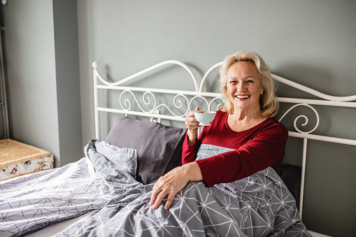 Senior woman wake up and she is drinking coffee in bed