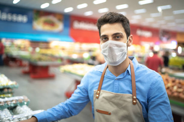 Portrait of young business man owner with face mask at supermarket Portrait of young business man owner with face mask at supermarket assistant photos stock pictures, royalty-free photos & images