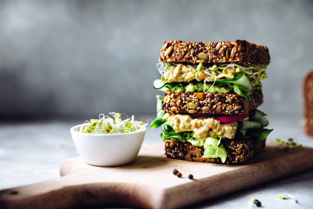 Vegan super sandwich served with sprouts Vegetarian sandwich made with sourdough bread, avocado creme, cucumber, radish and remoulade sauce with bowl of sprouts served on a table. salad photos stock pictures, royalty-free photos & images