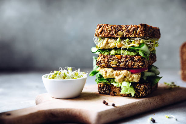 Vegan super sandwich served with sprouts Vegetarian sandwich made with sourdough bread, avocado creme, cucumber, radish and remoulade sauce with bowl of sprouts served on a table. wholegrain stock pictures, royalty-free photos & images