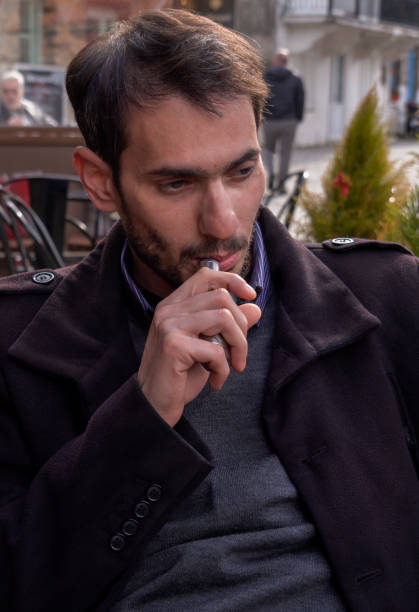 istock Young Man Vaping at Outdoor Cafe 1220390548