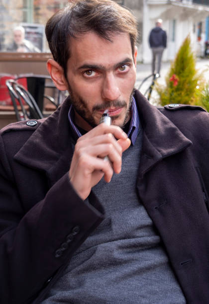 istock Young Man Vaping at Outdoor Cafe 1220391682