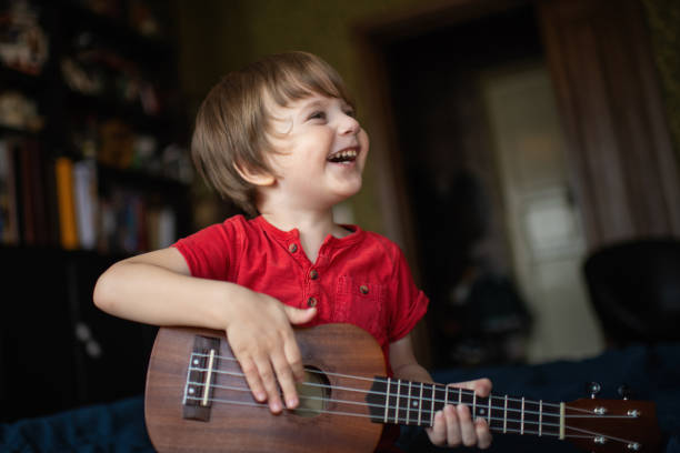 istock Cute little boy learning to play guitar in home 1220396585