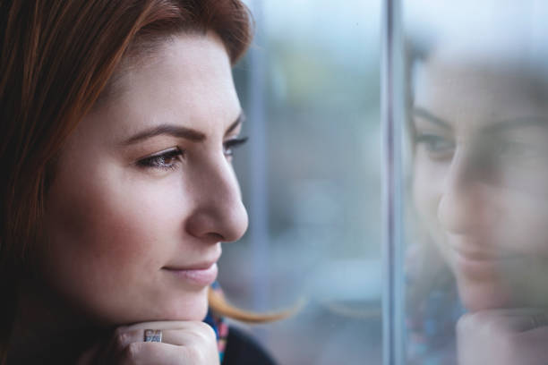 istock dreaming young woman looking out the window 1220398847