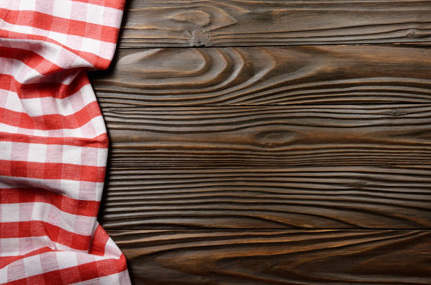 istock Red checkered napkin on brown wooden kitchen table with copy-space. Top view 1220398878