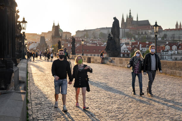 Half-empty Charles Bridge in Prague during the coronavirus pandemic, with people walking in protective face masks Prague, Czech Republic - April 16, 2020: Half-empty Charles Bridge during the coronavirus pandemic, with people walking in protective face masks former czechoslovakia stock pictures, royalty-free photos & images