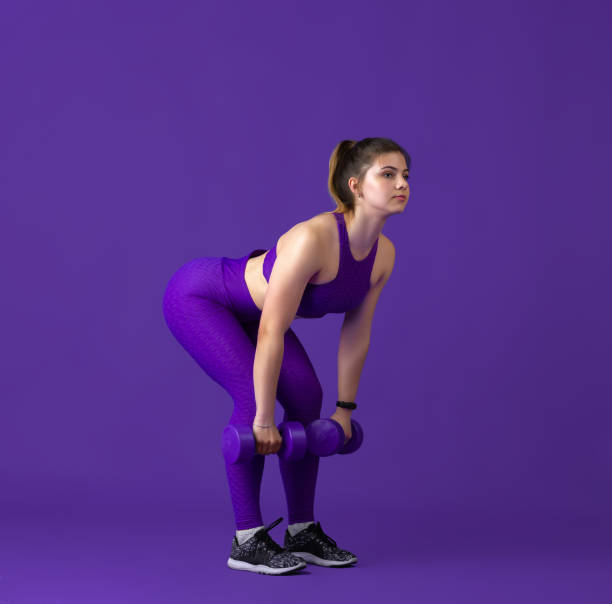 istock Beautiful young female athlete practicing on purple studio background, monochrome portrait 1220400115