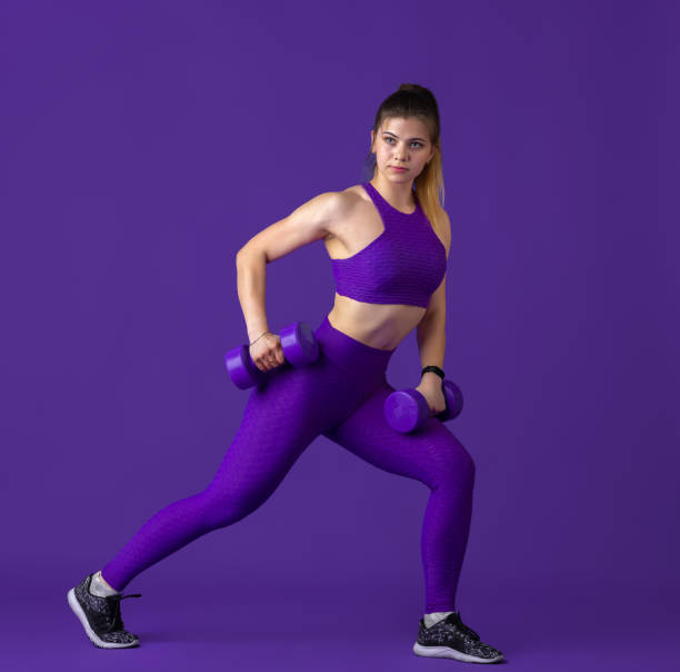 istock Beautiful young female athlete practicing on purple studio background, monochrome portrait 1220400121