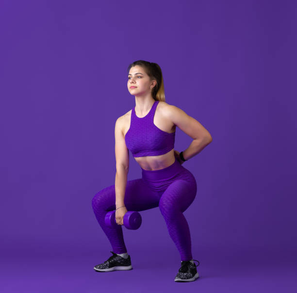 istock Beautiful young female athlete practicing on purple studio background, monochrome portrait 1220400125