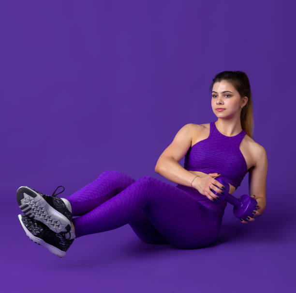 istock Beautiful young female athlete practicing on purple studio background, monochrome portrait 1220400135