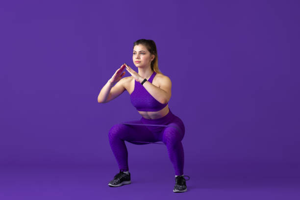 istock Beautiful young female athlete practicing on purple studio background, monochrome portrait 1220400155