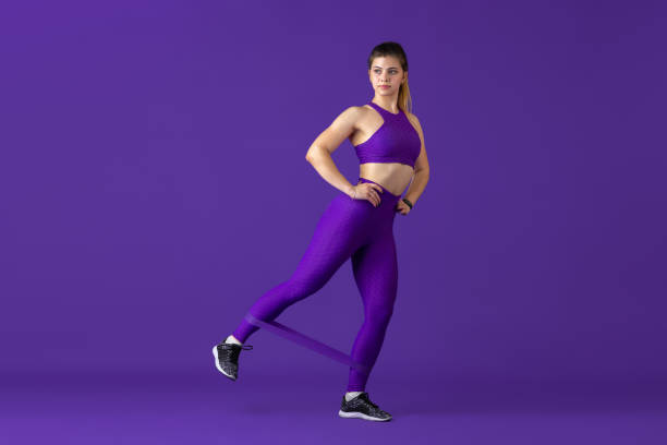 istock Beautiful young female athlete practicing on purple studio background, monochrome portrait 1220400161