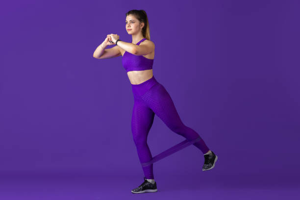 istock Beautiful young female athlete practicing on purple studio background, monochrome portrait 1220400163