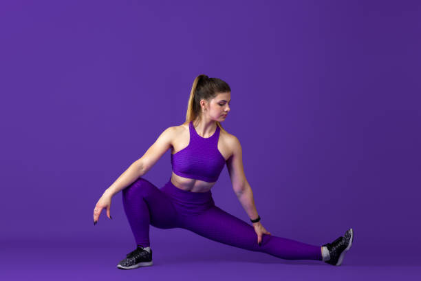 istock Beautiful young female athlete practicing on purple studio background, monochrome portrait 1220400166