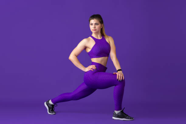istock Beautiful young female athlete practicing on purple studio background, monochrome portrait 1220400172