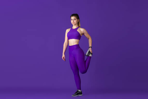 istock Beautiful young female athlete practicing on purple studio background, monochrome portrait 1220400193