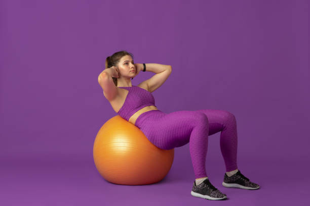 istock Beautiful young female athlete practicing on purple studio background, monochrome portrait 1220400200