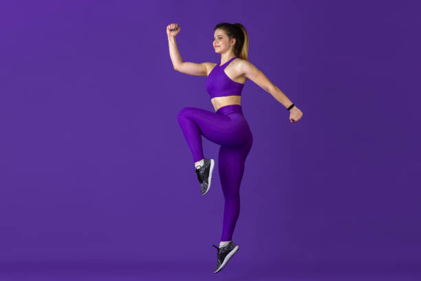 istock Beautiful young female athlete practicing on purple studio background, monochrome portrait 1220400203