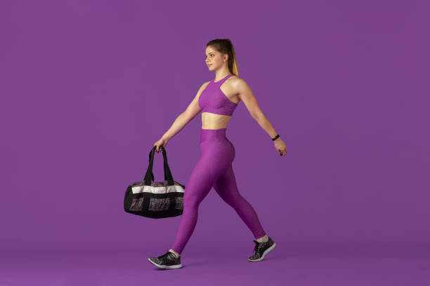 istock Beautiful young female athlete practicing on purple studio background, monochrome portrait 1220400206