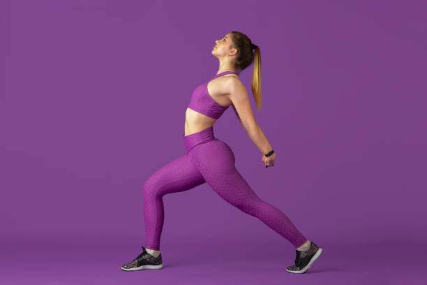 istock Beautiful young female athlete practicing on purple studio background, monochrome portrait 1220400212