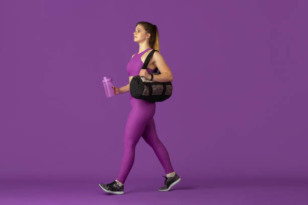 istock Beautiful young female athlete practicing on purple studio background, monochrome portrait 1220400220