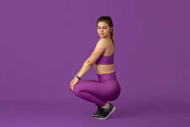 istock Beautiful young female athlete practicing on purple studio background, monochrome portrait 1220400231