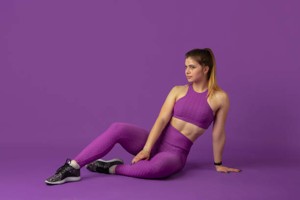 istock Beautiful young female athlete practicing on purple studio background, monochrome portrait 1220400235