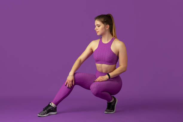 istock Beautiful young female athlete practicing on purple studio background, monochrome portrait 1220400242