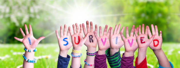 istock Children Hands Building Word I Survived, Grass Meadow 1220400377