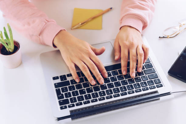istock Woman hands working at laptop on a white marble desk. 1220401415