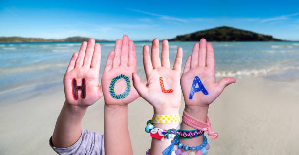 istock Kids Hands Holding Word Hola Means Hello, Ocean Background 1220401623