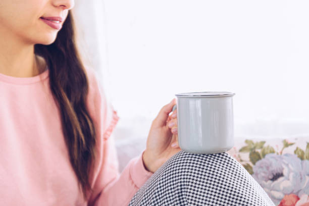 istock Young woman drinking coffee or tea sitting by the window 1220402604