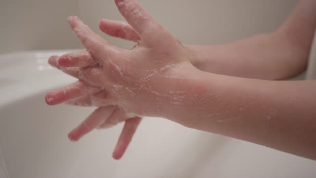 Close up of hands scrubbing thoroughly and making soap bubbles in slow motion