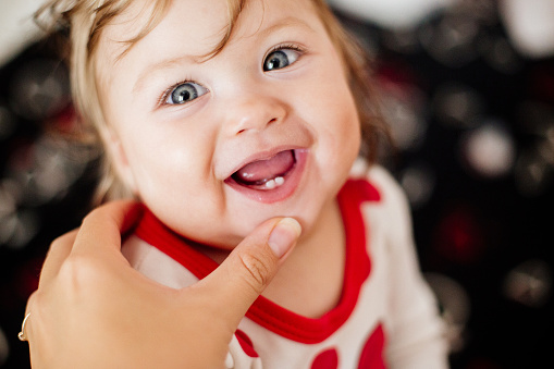 The first teeth of a child. Smile and laugh. Mom's hand.