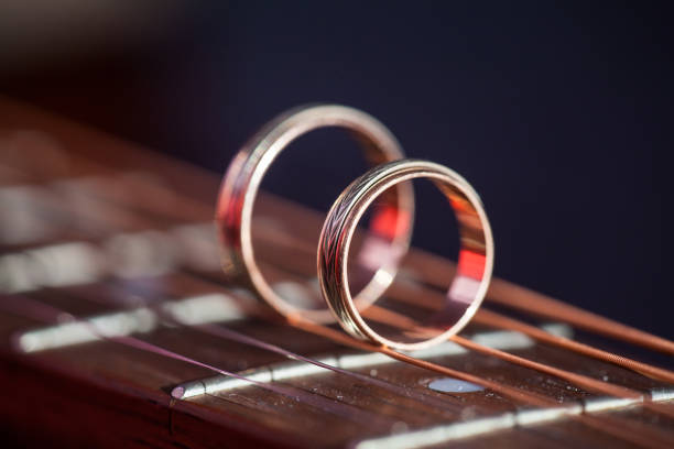 Two Wedding Rings on guitar strings. Two wedding rings standing on guitar fretboard