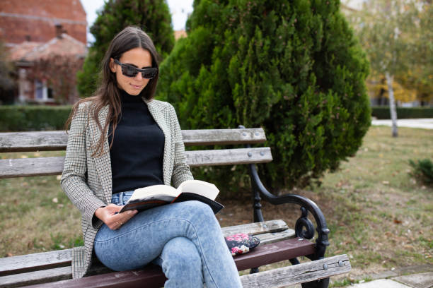 istock A young woman reading a book in the park 1220407306
