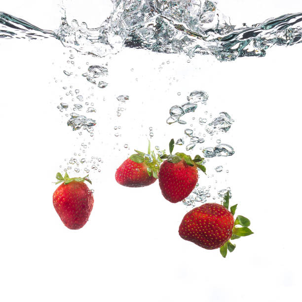 istock Red strawberries splashing on water in a white background 1220411648