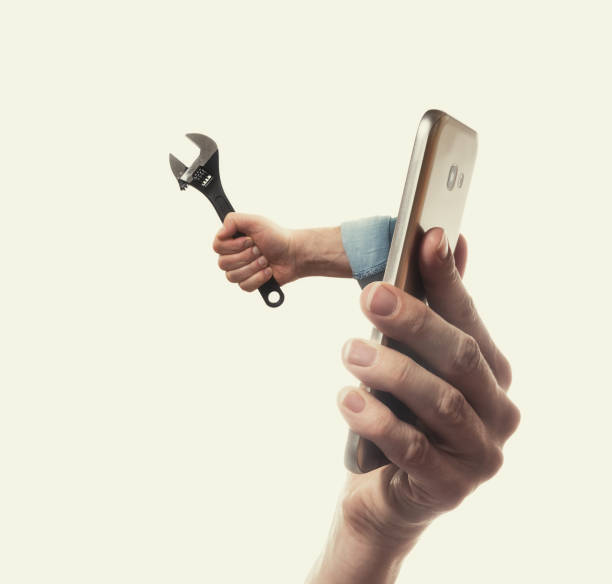 Concept of technical support. The human hand with black wrench stick out of a smartphone screen. Concept of technical support. telegram machine photos stock pictures, royalty-free photos & images
