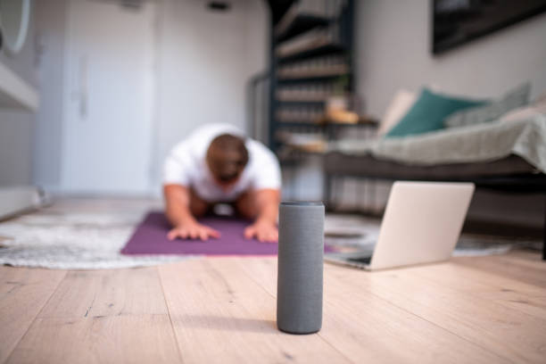 Close up of a bluetooth speaker. Close up of a bluetooth speaker. In the background we can see young man doing yoga on the mat in the living room teenage yoga stock pictures, royalty-free photos & images