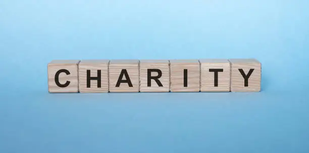 Photo of CHARITY word on wooden cube blocks on light blue background